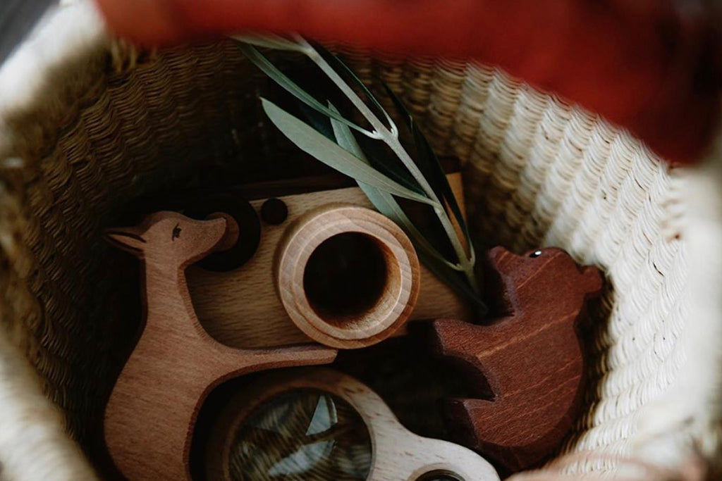 A basket of animal-shaped wooden toys and a wooden toy camera, crafted from non-toxic, biodegradable materials for eco-friendly, creative play, evoking a natural and eco-friendly vibe.