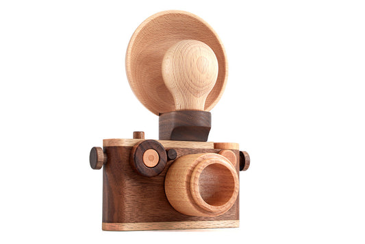 Vintage-inspired wooden toy camera with detachable light bulb flash, crafted from solid wood for imaginative pretend play.