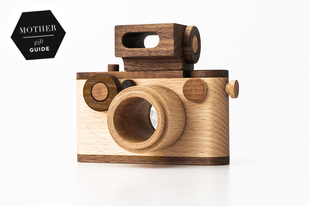 close-up of a wooden toy camera inspired by vintage 35MM design, featuring a kaleidoscopic lens, detachable magnetic flash, and clickable buttons, made from natural walnut and beechwood.