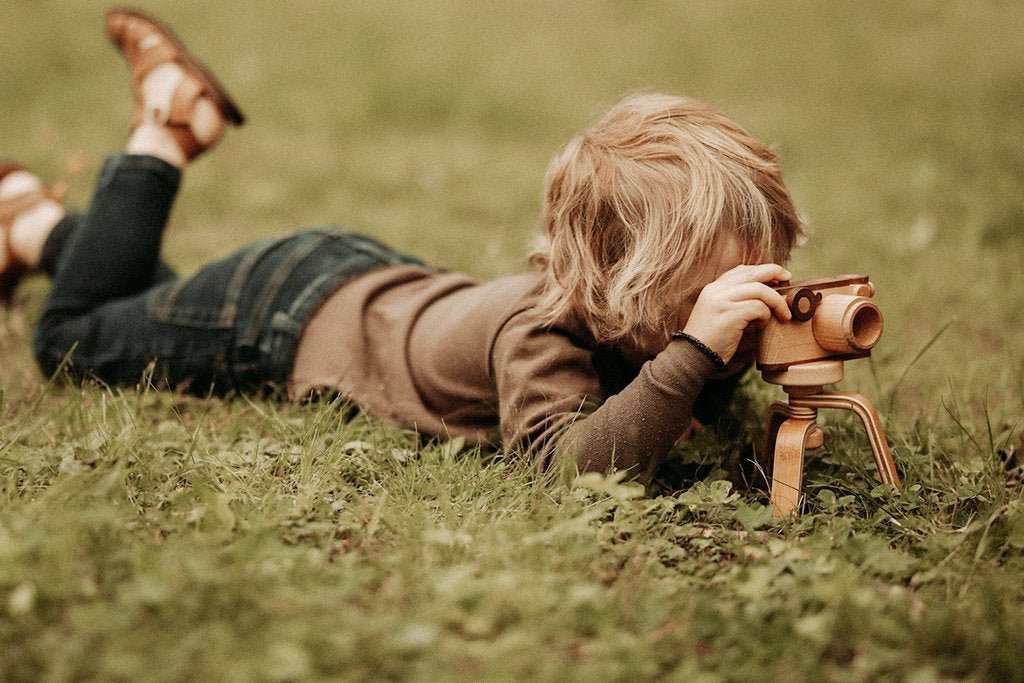 Father's Factory 35MM Original wooden toy camera, value gift set. great kids camera. high quality wooden toys. toys that double as interior decor. perfect for pretend play, imaginary play, and play outside. Picture shows a boy taking photos with father's factory wooden toy camera.