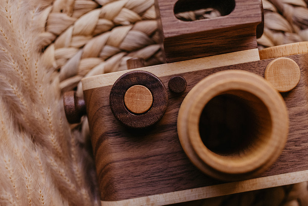 Close-up of a vintage-inspired wooden toy camera with a clickable button and flash, made from non-toxic materials, ideal for creative play.