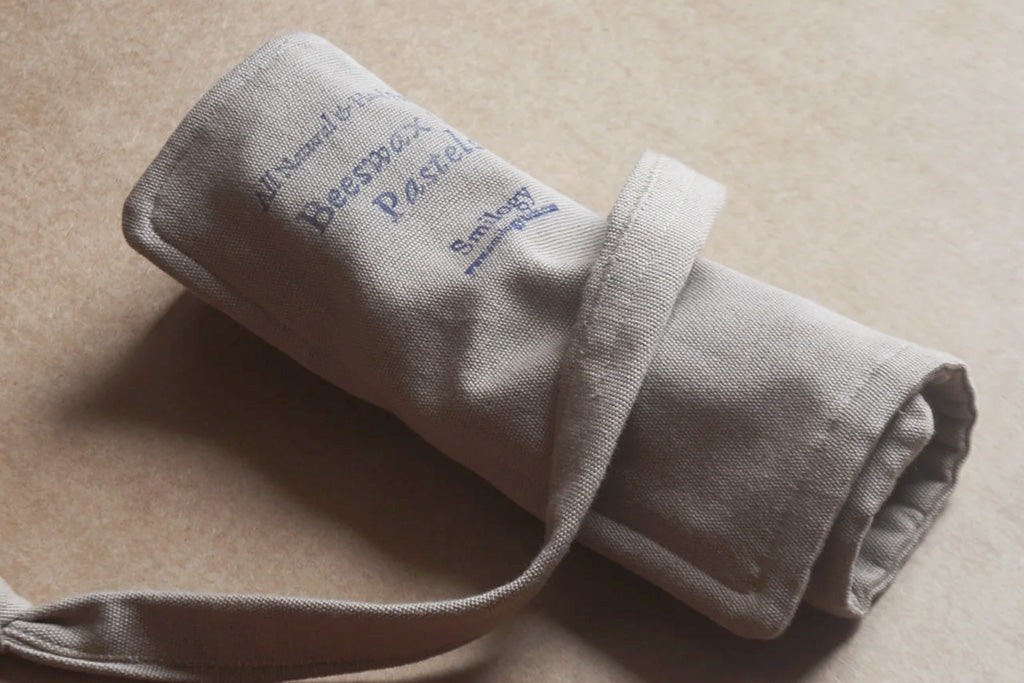 Set of ten organic beeswax crayons in earthy and primary colors stored in a gray canvas roll-up pouch