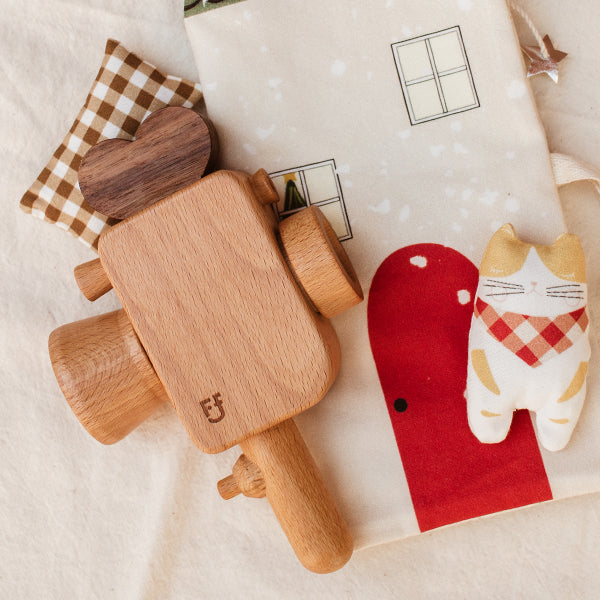 a wooden toy camera inspired by the super 8 camera is laying on top of christmas fabrics and sewing patterns.