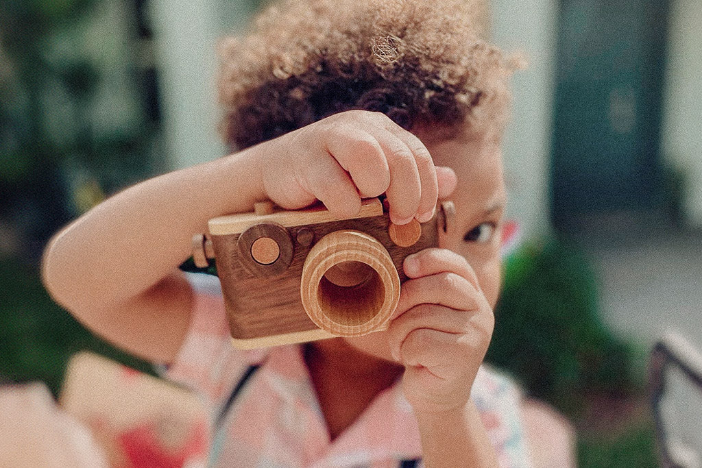 35MM camera style wooden toy camera with detachable magnetic flash, clickable button, and kaleidoscopic lens. It’s the perfect toy camera for pretend play, sensory play, and homeschooling. This camera for kids is made of walnut and beechwood with heirloom quality. Non-toxic wooden toys, child-led play wood toys, wooden toys for children, and environmental friendly toy. Tested To Meet All Safety Standards. The wooden toy camera can be an interior decor item for a kid’s room.